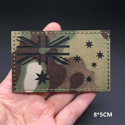 Camouflage patch with Australian flag design held in a hand against a dark background