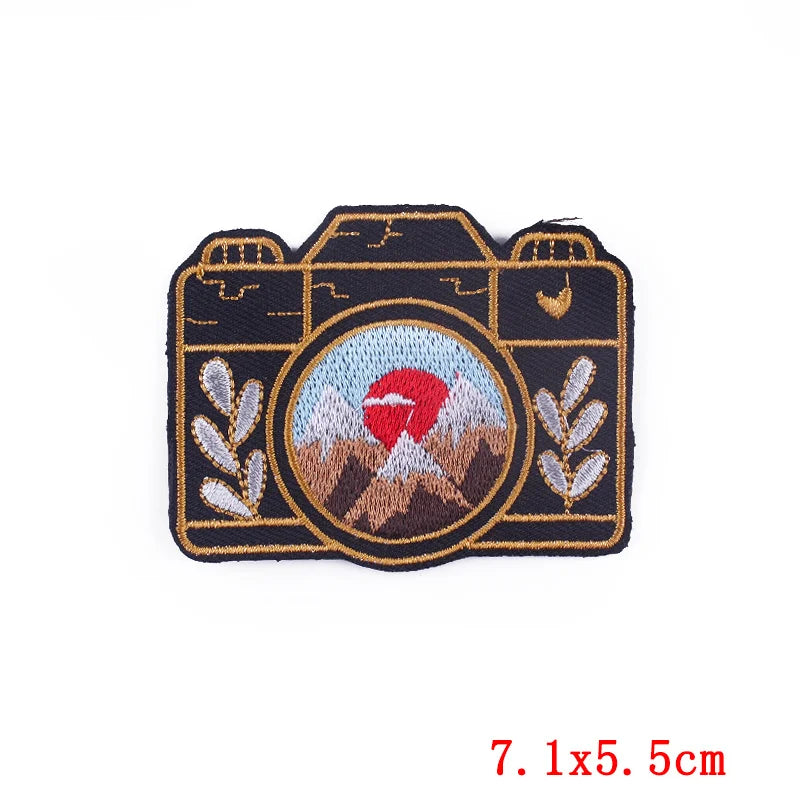 Camera-shaped patch with embroidered design on a white background