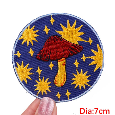 Circular patch with red mushroom and yellow stars on a blue background, held by a hand.