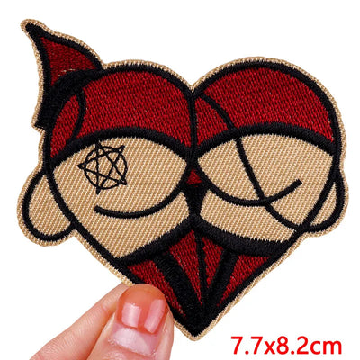 Heart-shaped patch with a stylized face design held by a hand, on a white background.