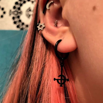 Close-up of an ear with black earrings and pink hair.