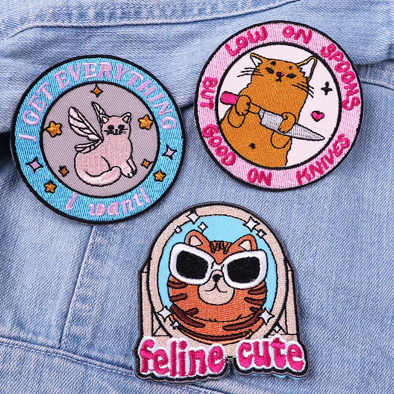 Three cat-themed patches on a denim background