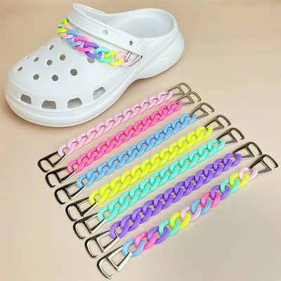 White clog shoe with colorful chain strap on a beige background