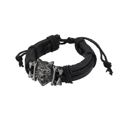 Black woven bracelet with a wolf head charm on a white background