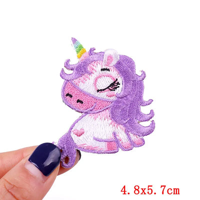 Embroidered unicorn patch held by a hand with a white background