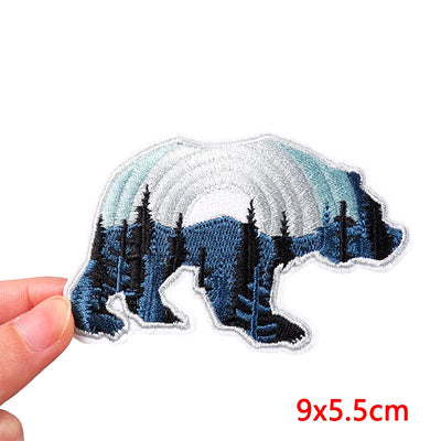 Polar bear patch with forest design held by a hand on a white background