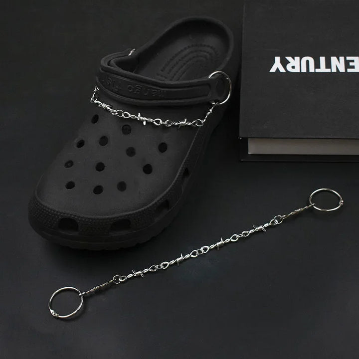 Black clog shoe with a chain attached on a dark background