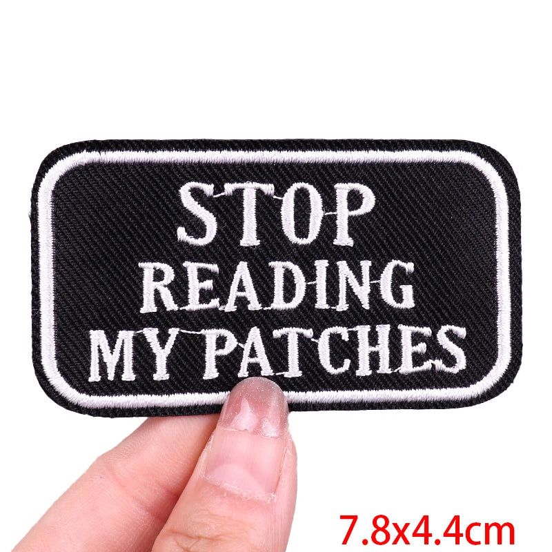 Black patch with white text 'STOP READING MY PATCHES' held by a hand, with size label '7.8x4.4cm'.