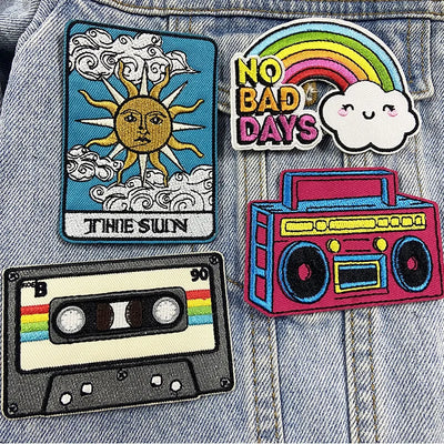 Four colorful patches on a denim background, including 'This Sun', 'No Bad Days', '90s Cassette', and 'Radio'.