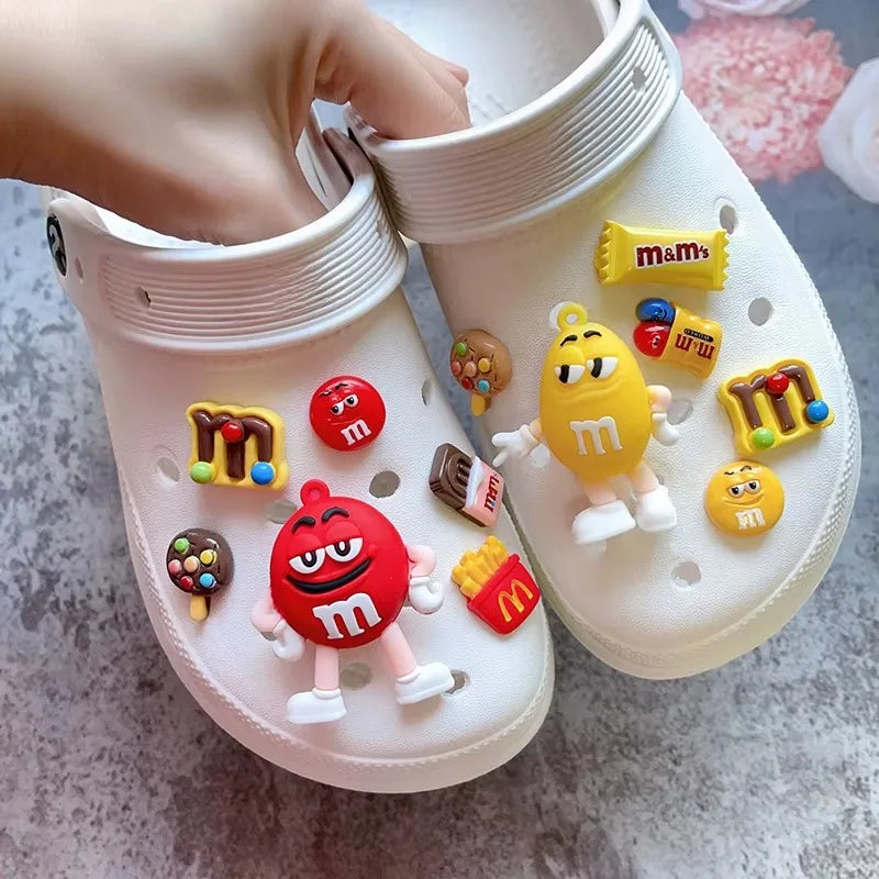 White clogs with colorful M&M character charms on a light gray surface.