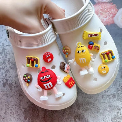 White clogs with colorful M&M character charms on a light gray surface.