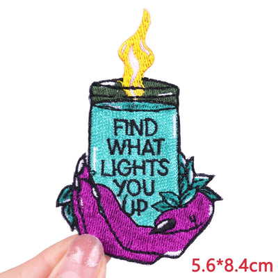 Embroidered patch of a candle with text held by a hand on a white background