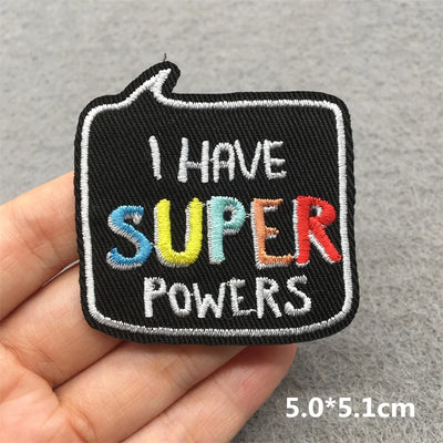 Embroidered patch with 'I HAVE SUPER POWERS' text held by a hand on a gray background
