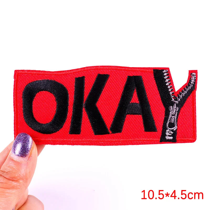 Red patch with 'OKAY' text held by a hand on a white background
