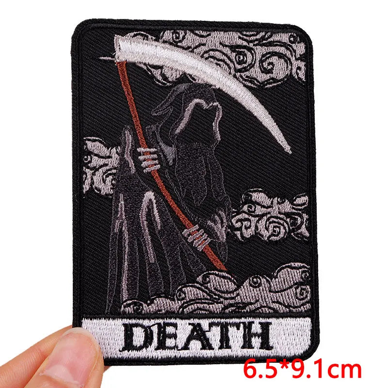 Embroidered patch with a Grim Reaper design and 'DEATH' text, held by a hand.