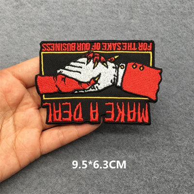 Embroidered patch with handshake design held by a hand on a gray background
