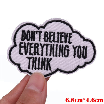 Embroidered patch with text 'Don't believe everything you think' held by a hand on a white background.