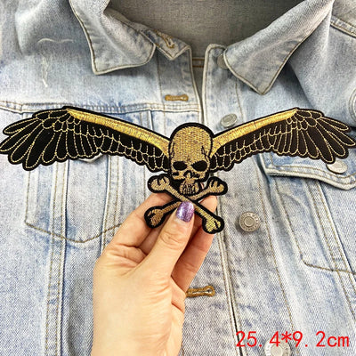 Skull with wings and crossbones patch held over a denim jacket