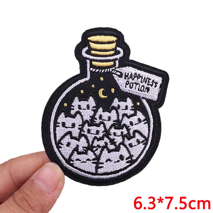 Embroidered patch of a potion bottle with cats and &