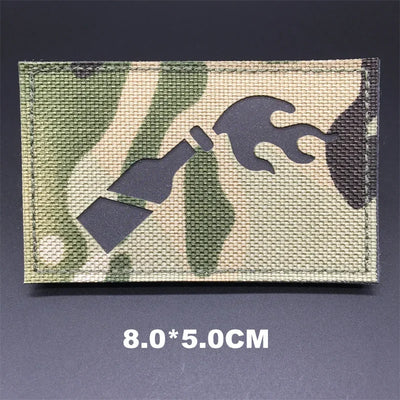 Camouflage patch with tool symbol and size label on a dark background