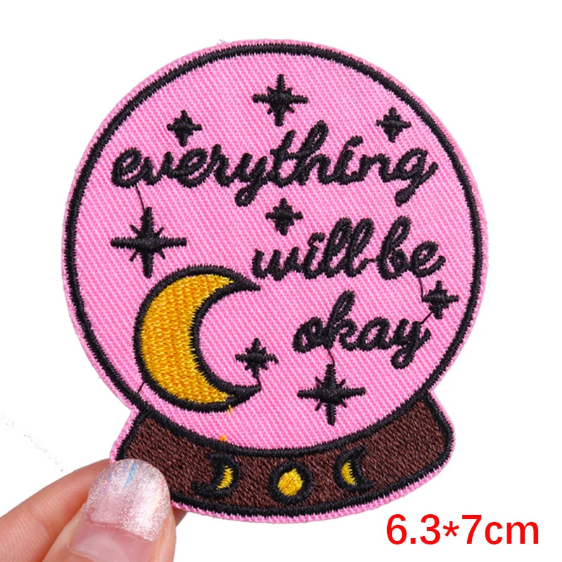 Pink patch with 'everything will be okay' text and a crystal ball design held by a hand.