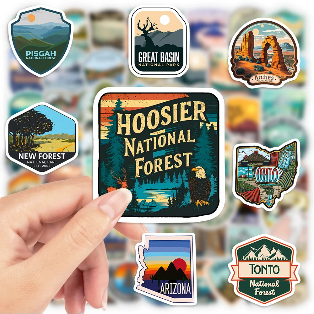 Collection of national park stickers with a focus on Hoosier National Forest sticker held by a hand.