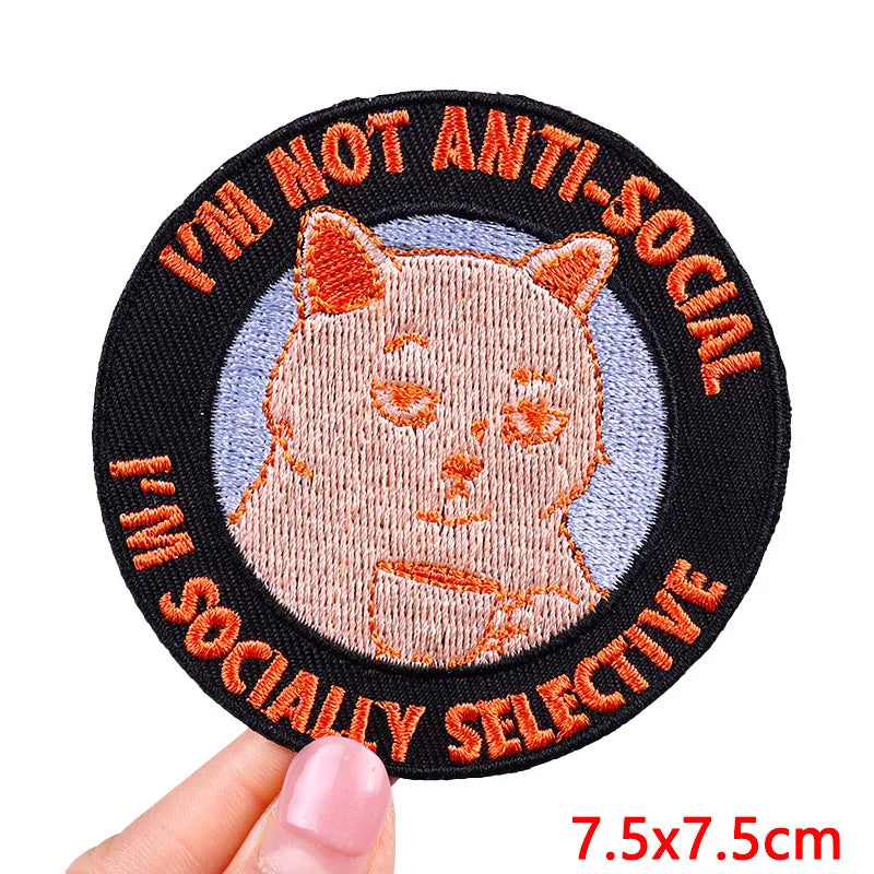 Circular patch with a cat illustration and text 'I'm not anti-social, I'm socially selective' held by a hand.