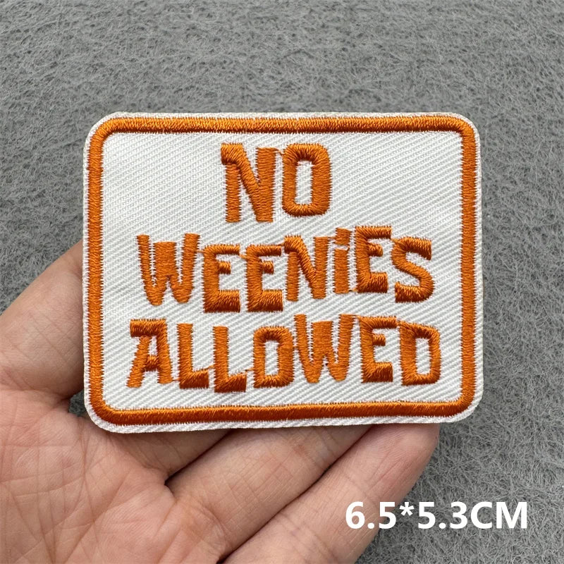 Embroidered patch with 'No Weenies Allowed' text held in a hand against a gray background.