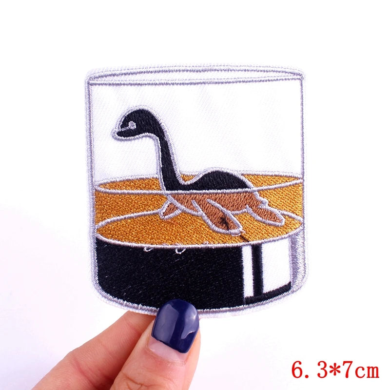 Patch with a dinosaur design held by a hand on a white background