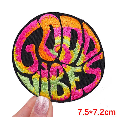 Colorful 'Good Vibes' patch held by a hand with a white background