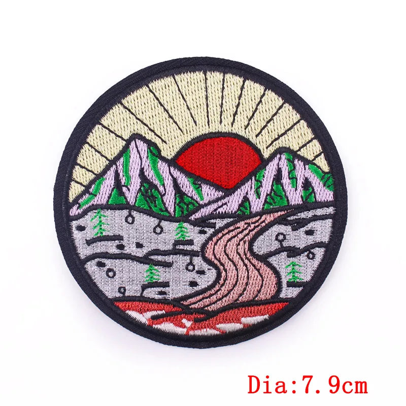 Round embroidered patch with mountain and sun design on a white background