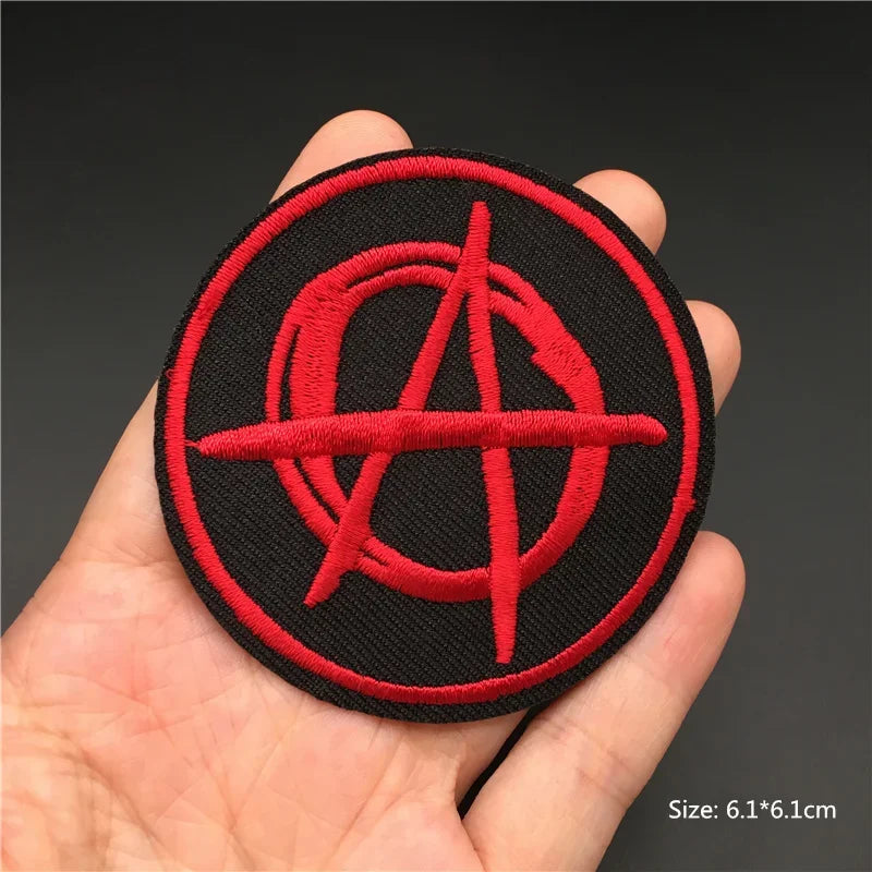Red anarchy symbol patch held in a hand with a dark background