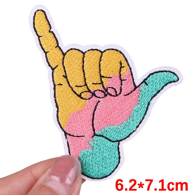Colorful hand gesture patch held by a hand with measurement text '6.2*7.1cm'.