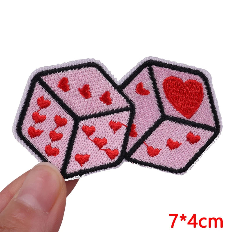 Two pink dice-shaped patches with red hearts on a white background