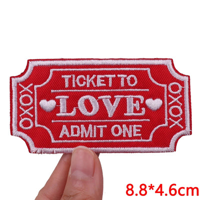Red patch with 'Ticket to Love Admit One' text held by a hand on a white background