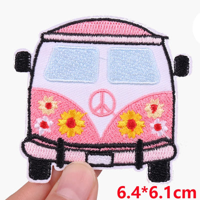 Embroidered patch of a pink van with flowers and a peace symbol, held by a hand.