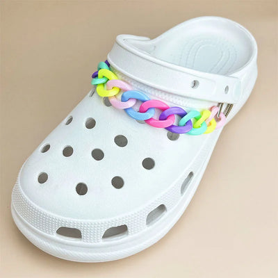 White clog shoe with a colorful chain strap on a beige background