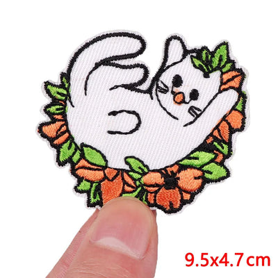Embroidered patch of a ghost surrounded by pumpkins held between fingers with size label.