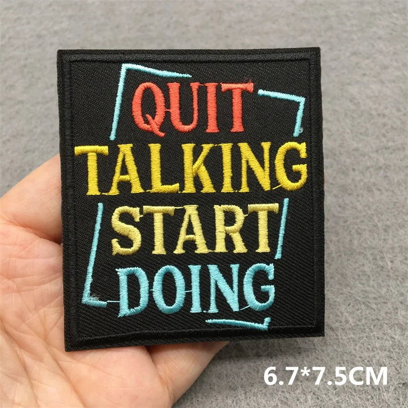 Embroidered patch with motivational text held in a hand on a gray background