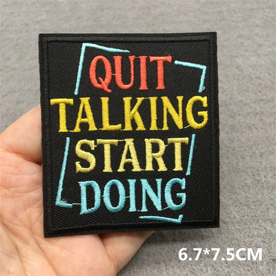 Embroidered patch with motivational text held in a hand on a gray background