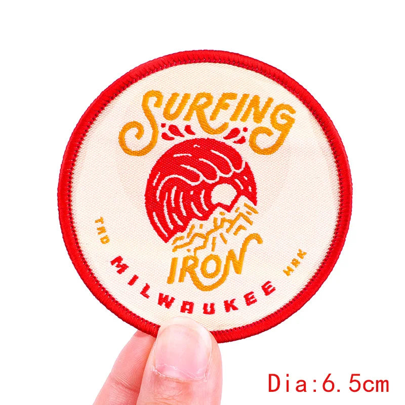 Circular patch with 'Surfing Iron Milwaukee' design held by a hand, on a white background.