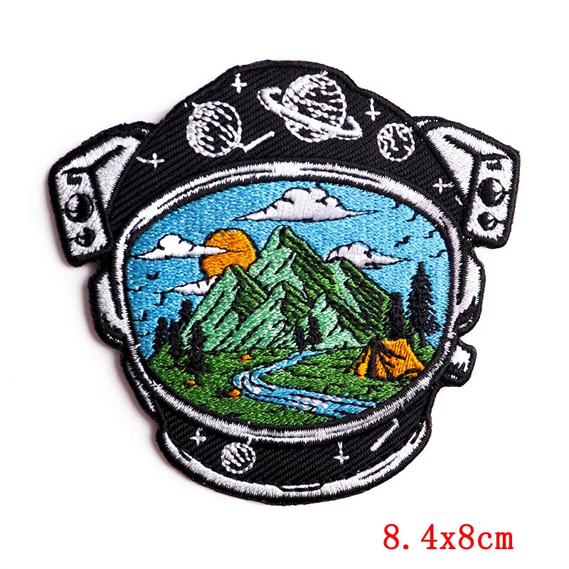 Embroidered patch with mountain and camping scene inside a space helmet design, size 8.4x8cm.