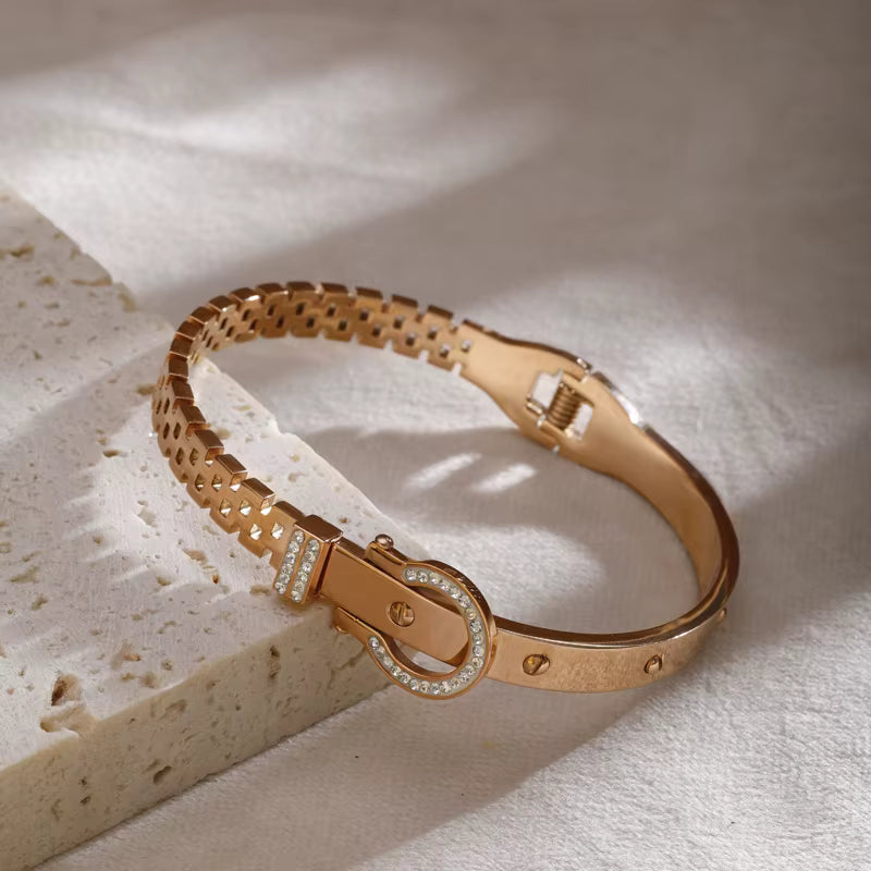 Rose gold bracelet with diamond accents on a textured beige surface