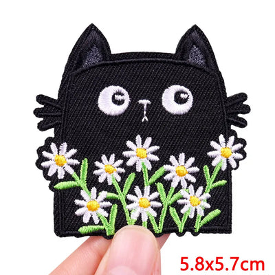 Black cat patch with white flowers held by a hand on a white background