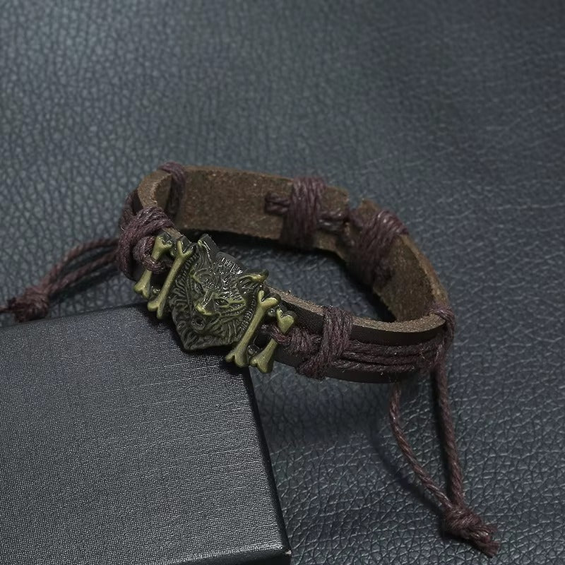 Brown leather bracelet with a metal wolf pendant on a textured gray surface