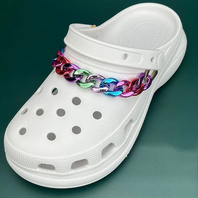 White clog shoe with a colorful chain on a green background