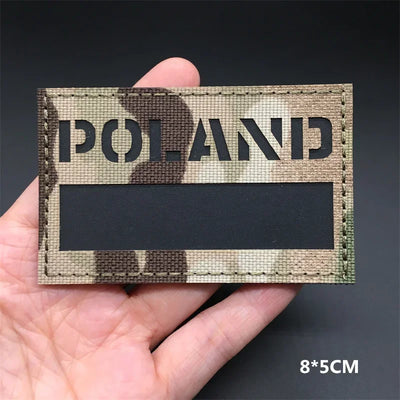 POLAND flag Camouflage patch held in a hand against a dark background