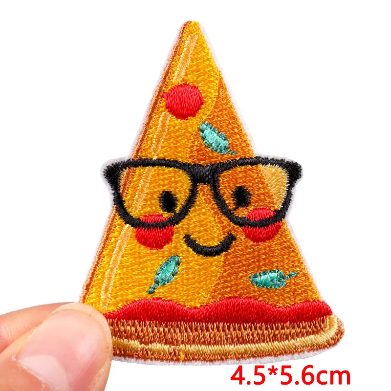 Embroidered patch of a smiling triangle character with glasses held by a hand on a white background.