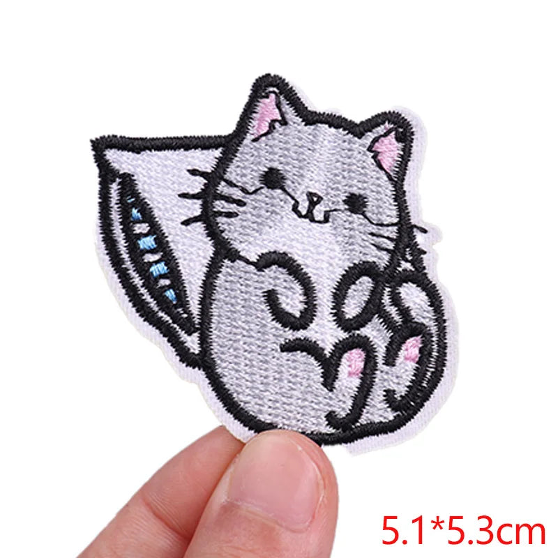 Embroidered cat patch held by a hand with dimensions displayed