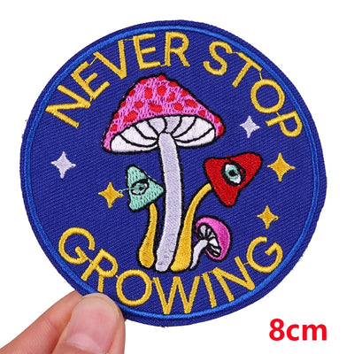 Circular patch with mushrooms and 'Never Stop Growing' text held by a hand, on a white background.